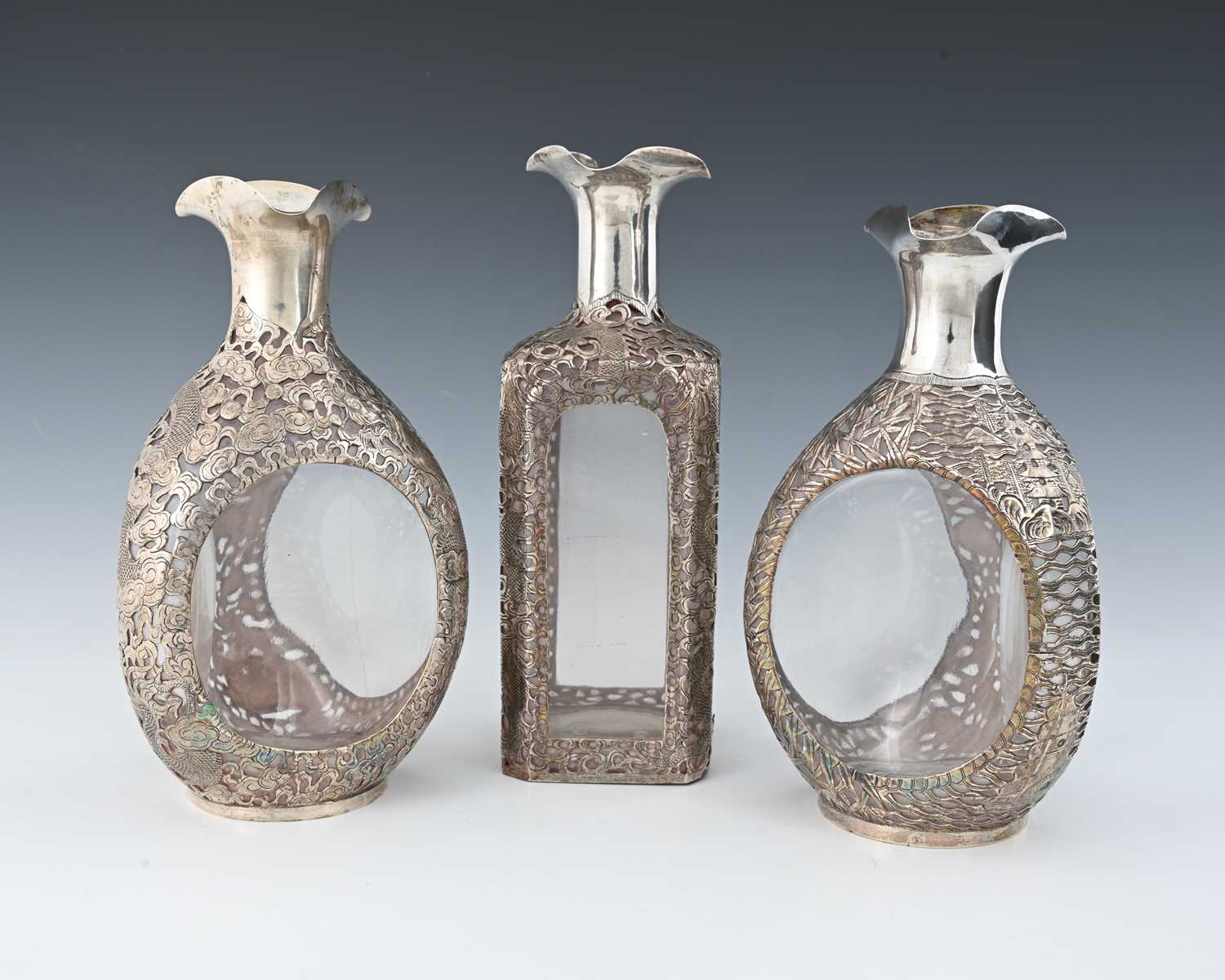 Lot 30 - China. Three Chinese silver overlay decanters,...
