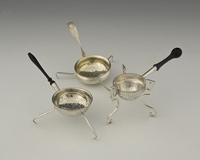 Lot 165 - Three silver-coloured metal tea strainers,...