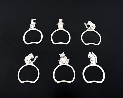 Lot 514 - A set of six silver novelty napkin rings, each...