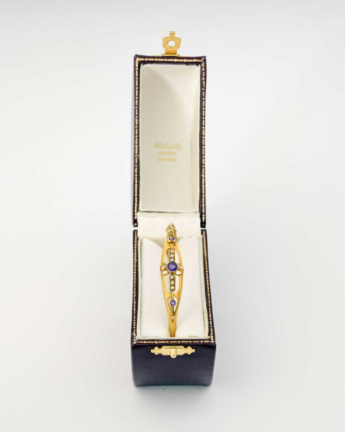 Lot 3 - An early 20th century 9ct gold amethyst and pearl bangle bracelet