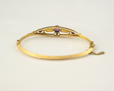 Lot 3 - An early 20th century 9ct gold amethyst and pearl bangle bracelet