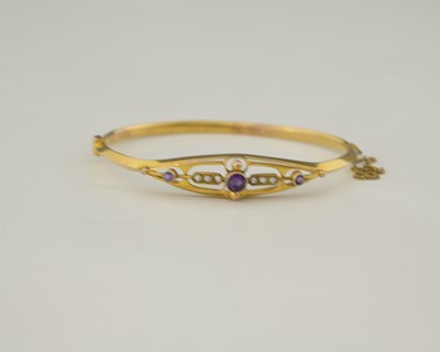 Lot 3 - An early 20th century 9ct gold amethyst and pearl bangle bracelet