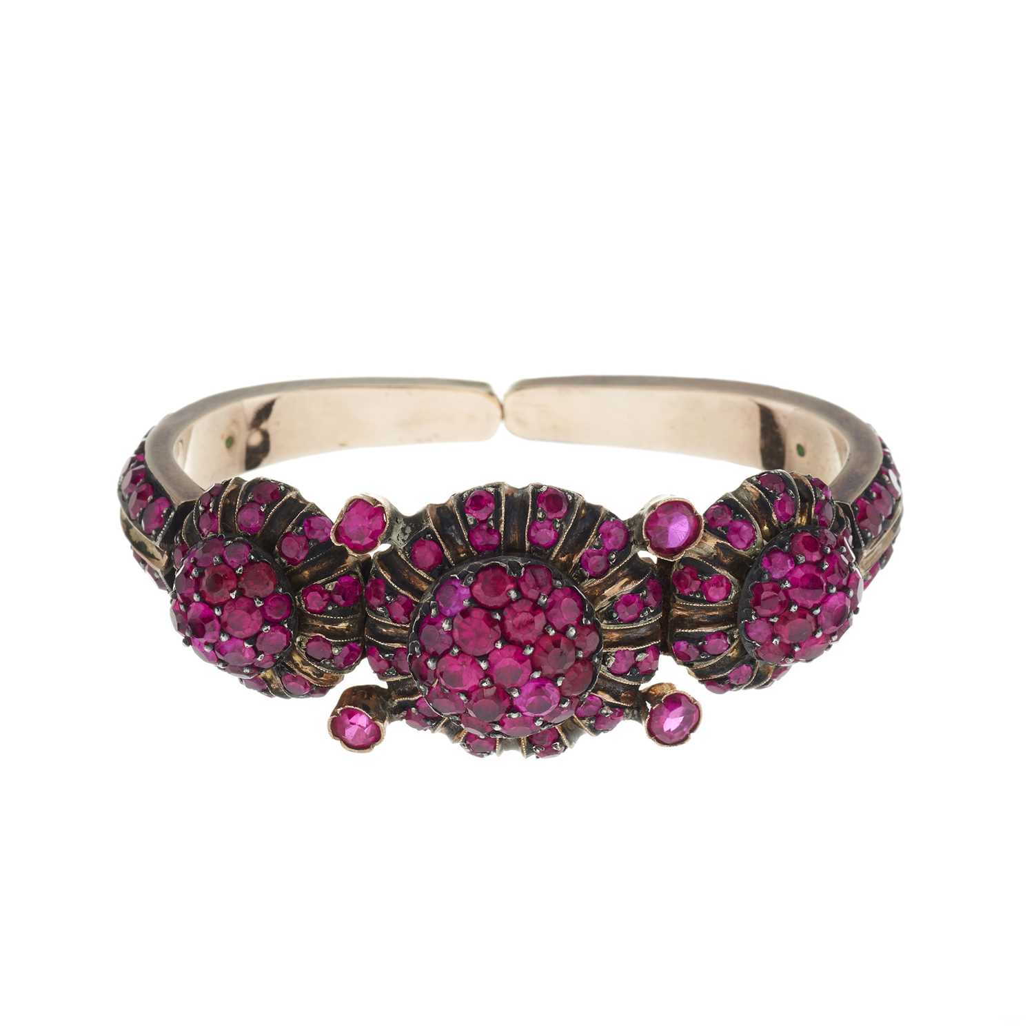 Lot 101 - A ruby triple cluster panel sprung torque bangle