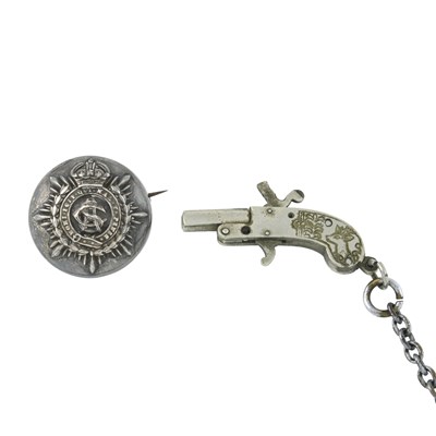 Lot 250 - An early 20th century white metal pistol fob and a military locket brooch