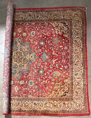 Lot 420 - A large Persian Sarouk rug: a red field with...